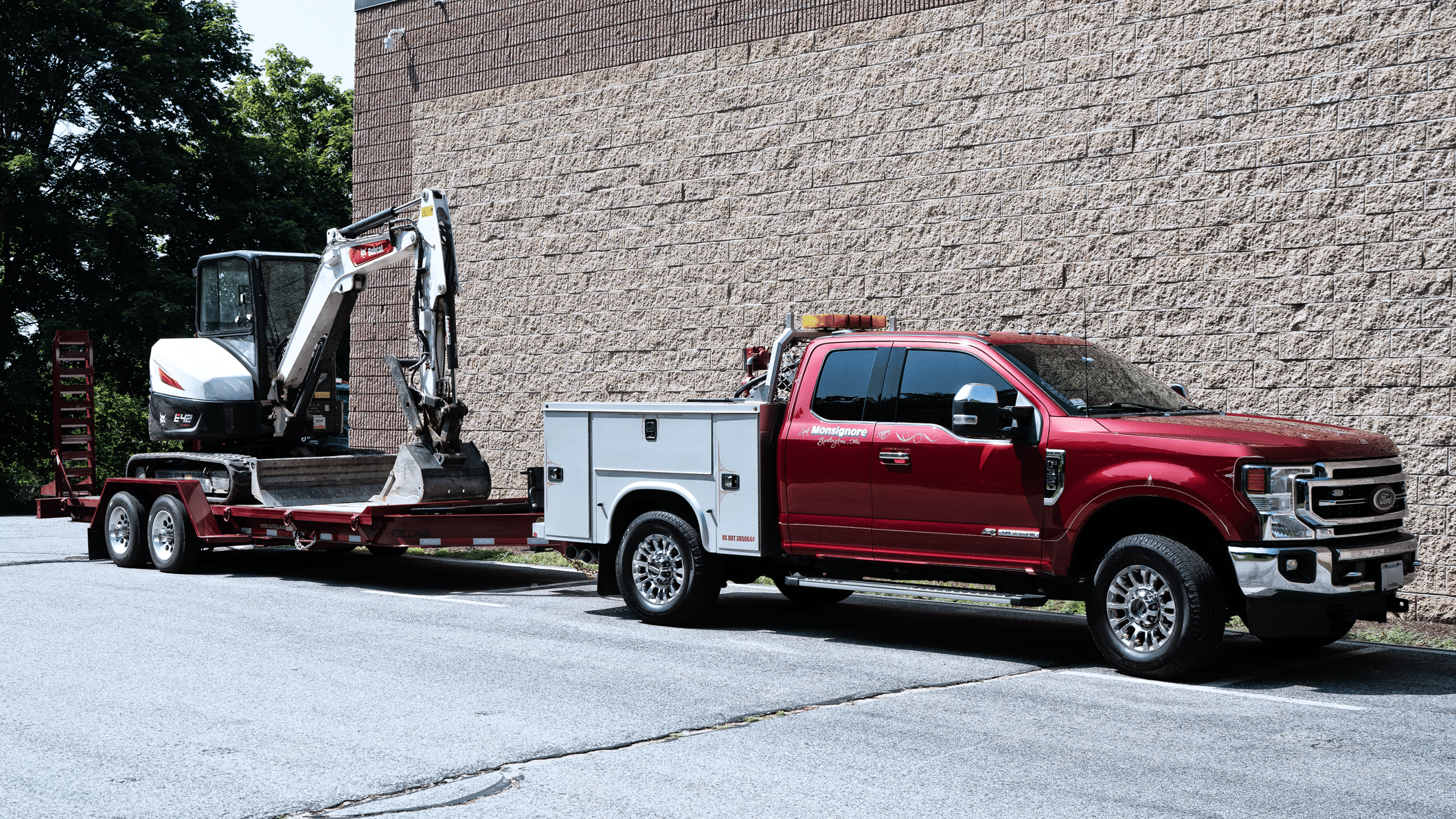 Monsignore Excavating service truck hooked up to a trailer with an excavator.