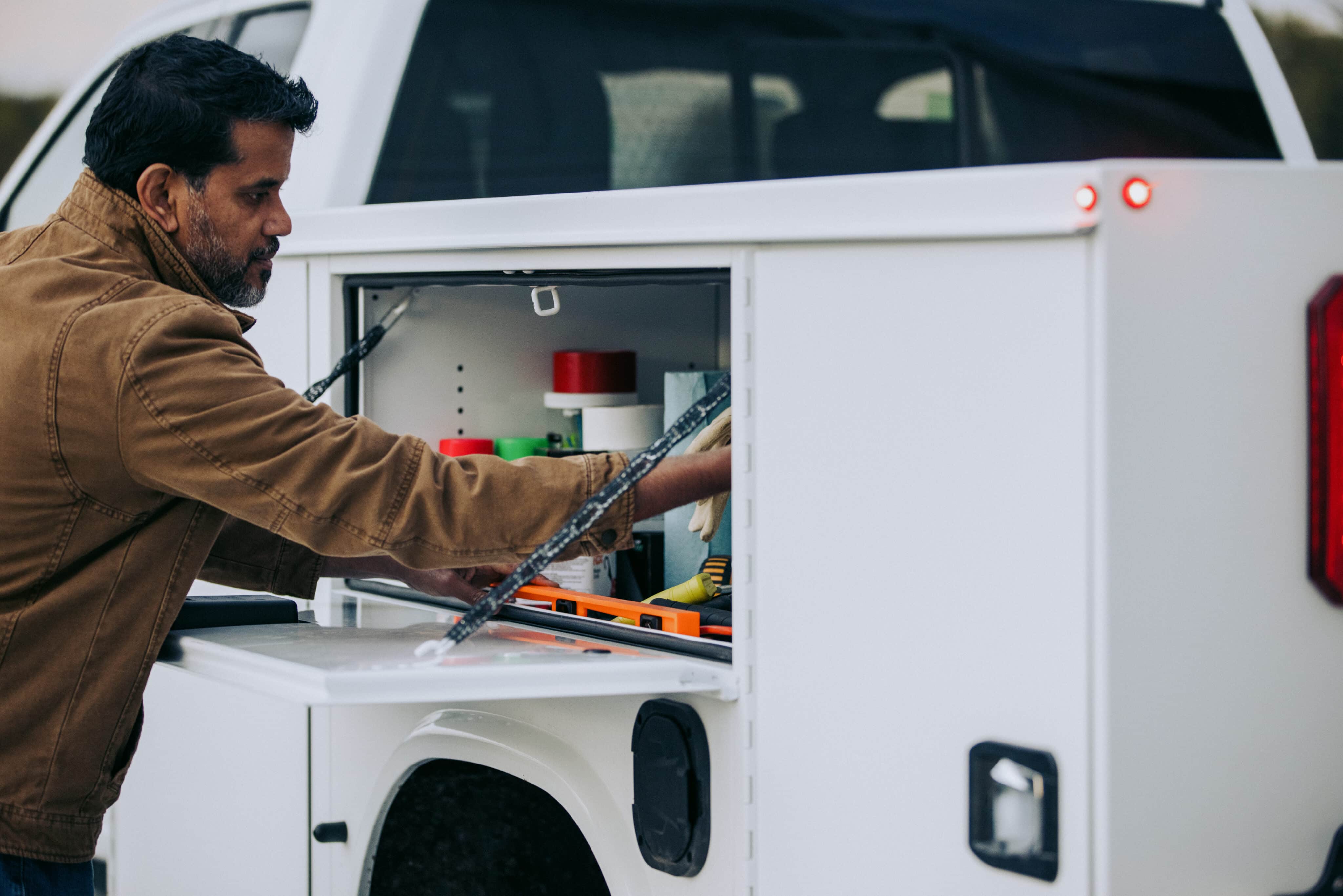 Male Worker Grabbing Cargo from Knapheide Service Truck Compartment